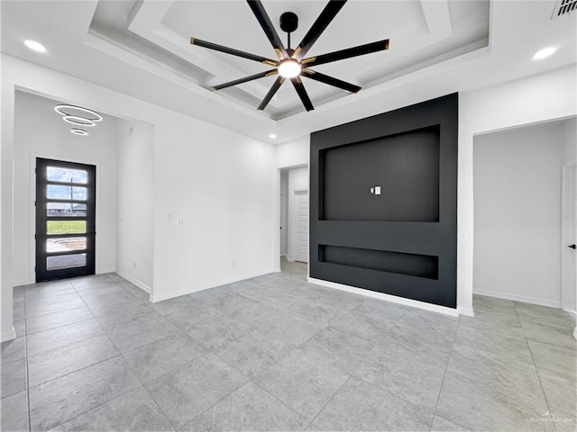 interior space with ceiling fan and a raised ceiling