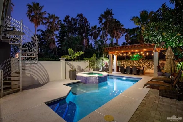 pool at twilight with a pool with connected hot tub, a patio, fence, and a pergola