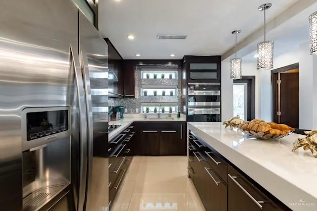 kitchen with visible vents, stainless steel appliances, dark brown cabinets, light countertops, and backsplash