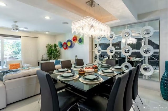 dining area with ceiling fan with notable chandelier, a raised ceiling, and recessed lighting