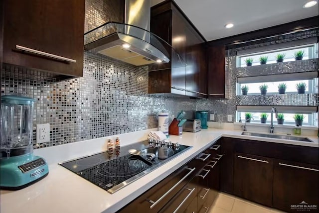 kitchen with black electric stovetop, light countertops, a sink, dark brown cabinets, and wall chimney exhaust hood