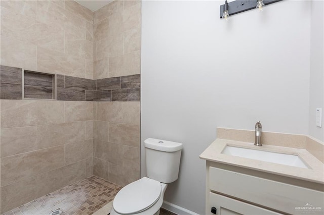 bathroom with vanity, toilet, and a tile shower