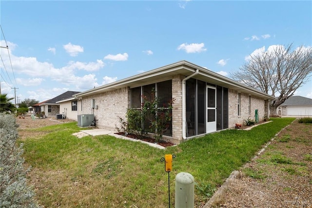 rear view of house featuring cooling unit, a yard, and a sunroom