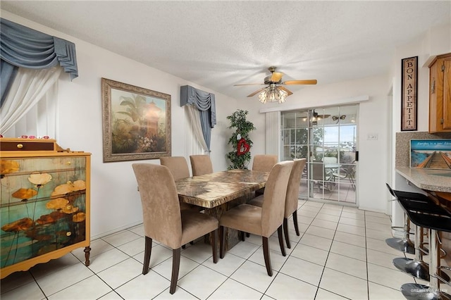 tiled dining room with a textured ceiling and ceiling fan