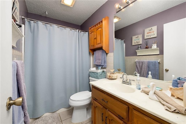 bathroom with tile patterned floors, toilet, tile walls, a textured ceiling, and vanity