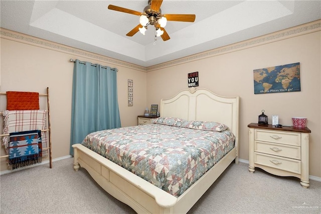 bedroom featuring light carpet, a raised ceiling, and ceiling fan