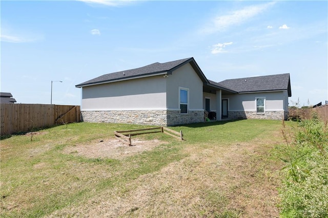 3702 Bea Ave, Harlingen, TX 78552 - rear view of house featuring stucco siding, fence, stone siding, and a lawn