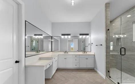 full bathroom featuring double vanity, a stall shower, and a sink