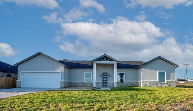 view of front of home with concrete driveway, stone siding, an attached garage, a front lawn, and stucco siding