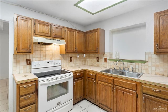 2408 River Oaks Ln, Edinburg, TX 78539 - kitchen featuring white range with electric stovetop, under cabinet range hood, a sink, brown cabinetry, and tile counters