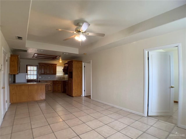 9401 N Fm 1015, Mercedes, TX 78570 - kitchen with a peninsula, a raised ceiling, light tile patterned flooring, ceiling fan, and baseboards