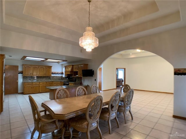 9401 N Fm 1015, Mercedes, TX 78570 - dining area featuring a tray ceiling, arched walkways, light tile patterned floors, and baseboards