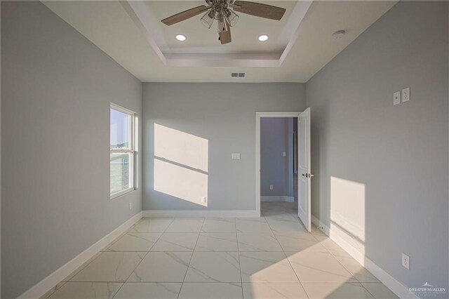 unfurnished room with a raised ceiling and ceiling fan