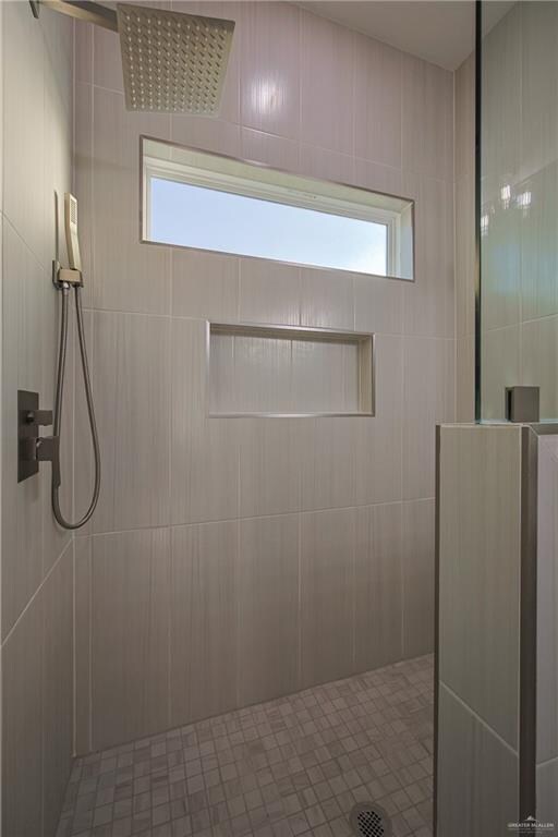 bathroom with tiled shower and tile walls