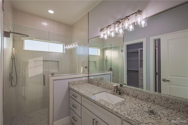 bathroom with vanity, a shower with door, and a healthy amount of sunlight