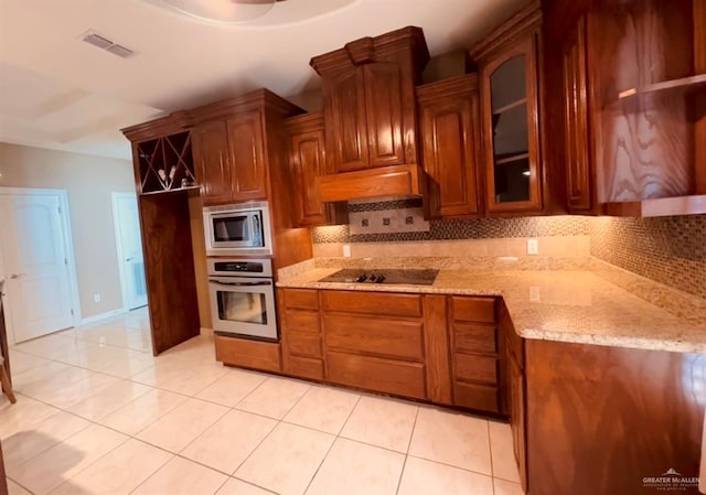 kitchen featuring light tile patterned flooring, light stone counters, stainless steel appliances, and tasteful backsplash