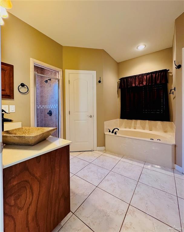 bathroom featuring tile patterned floors, vanity, and shower with separate bathtub