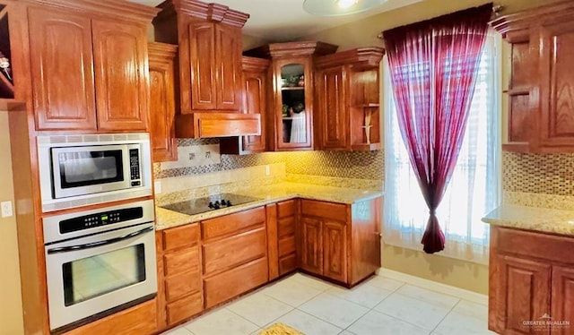 kitchen featuring light tile patterned floors, stainless steel appliances, light stone counters, and tasteful backsplash