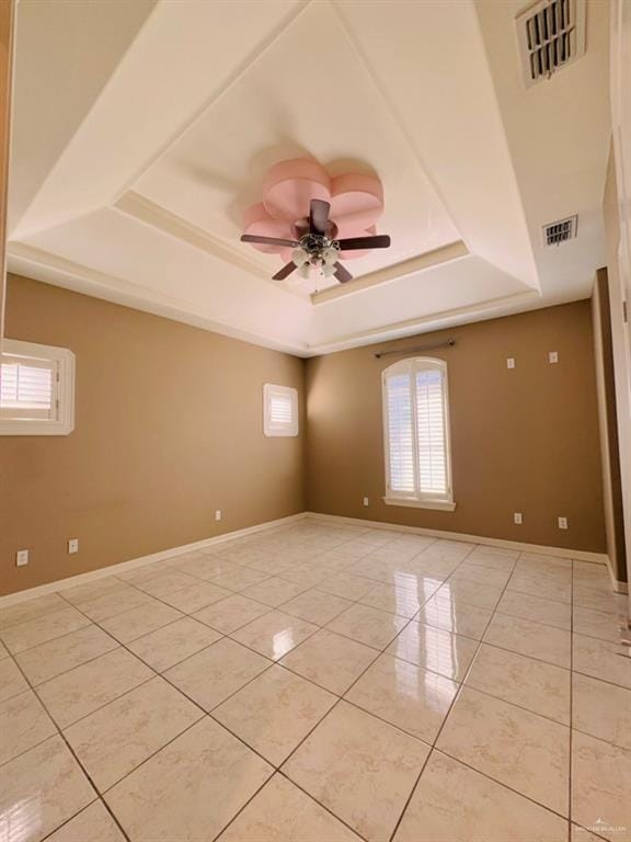 unfurnished room with light tile patterned floors, a tray ceiling, and ceiling fan