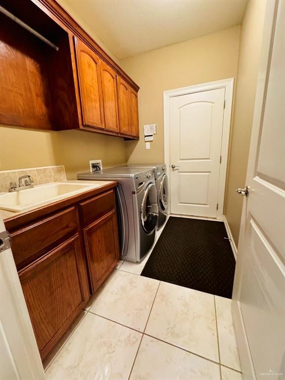 washroom featuring light tile patterned flooring, cabinets, sink, and washing machine and dryer