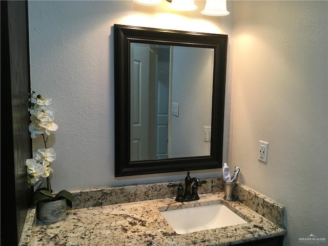 bathroom with a textured wall and vanity