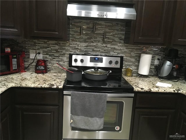 kitchen with tasteful backsplash, light stone counters, stainless steel electric range, and extractor fan