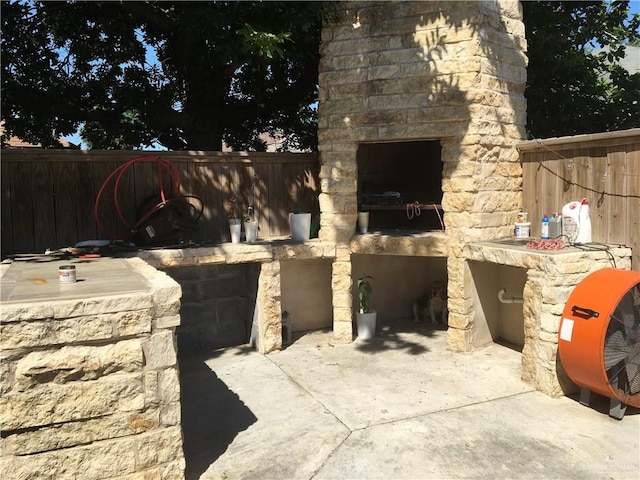 view of patio with a fenced backyard and a fireplace