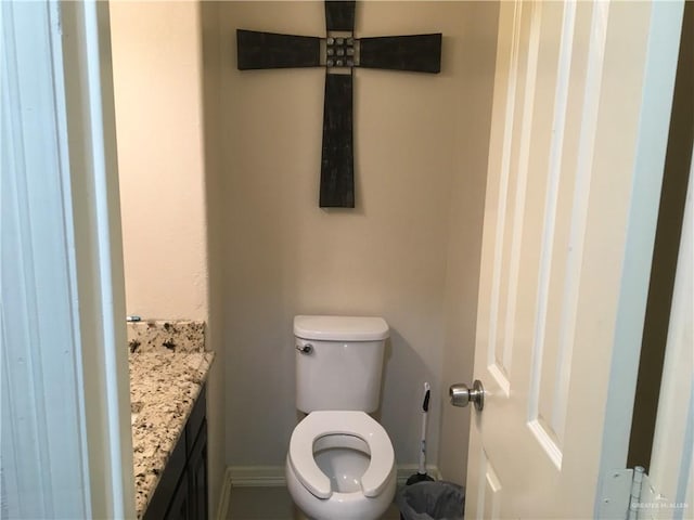 half bath featuring toilet, vanity, and baseboards