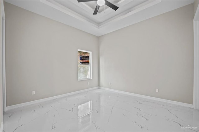 spare room featuring ceiling fan and a raised ceiling