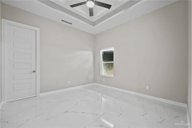 spare room featuring a tray ceiling and ceiling fan