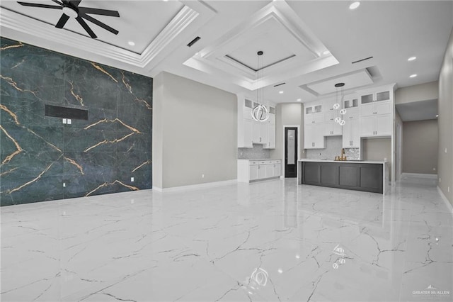 unfurnished living room with crown molding, ceiling fan, a tray ceiling, and sink