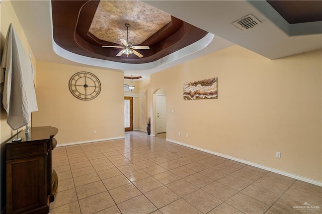 living room featuring ceiling fan, light tile patterned flooring, and a tray ceiling