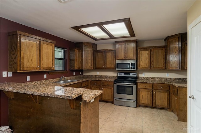 kitchen with stone counters, sink, stainless steel appliances, kitchen peninsula, and a breakfast bar area