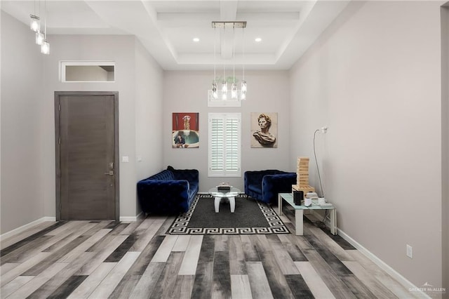 living area with beam ceiling, recessed lighting, a high ceiling, wood finished floors, and baseboards