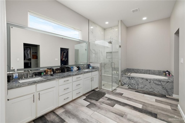 bathroom featuring double vanity, a sink, a marble finish shower, and wood finished floors