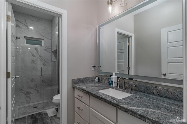 full bath with toilet, a marble finish shower, and vanity