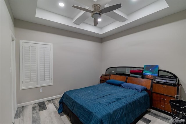 bedroom featuring a tray ceiling, baseboards, wood finished floors, and recessed lighting