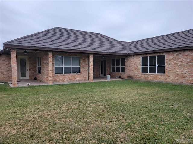 rear view of house featuring ceiling fan, a patio area, and a lawn