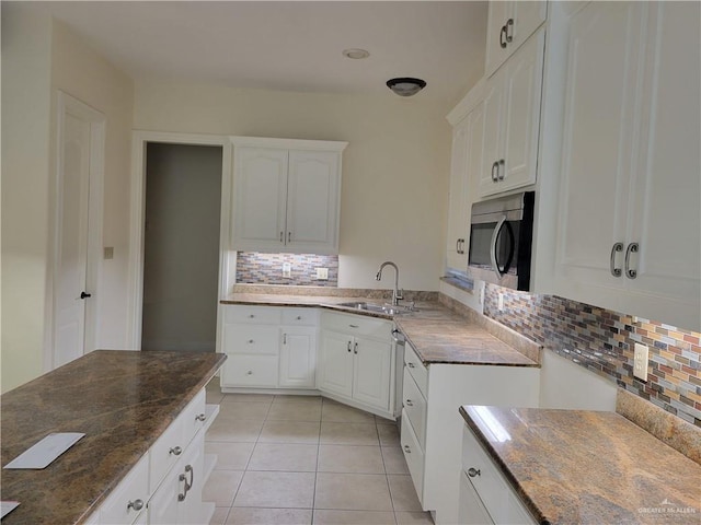 kitchen featuring backsplash, white cabinets, sink, dark stone countertops, and light tile patterned floors