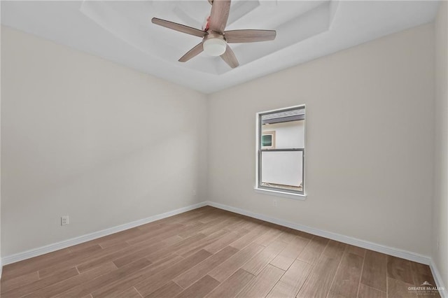 unfurnished room featuring a tray ceiling, light hardwood / wood-style flooring, and ceiling fan