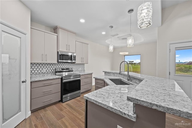 kitchen with decorative light fixtures, sink, an island with sink, and appliances with stainless steel finishes