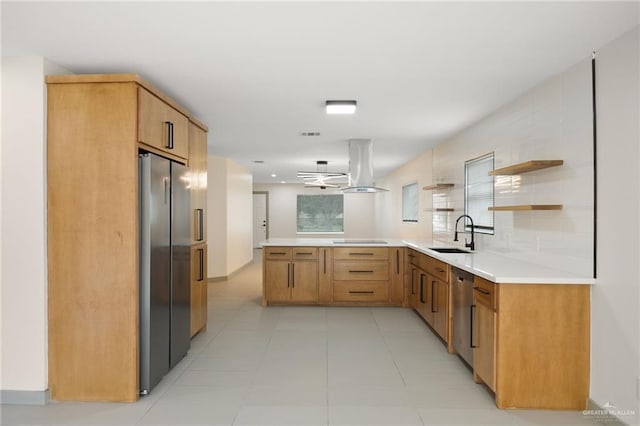 kitchen featuring kitchen peninsula, island range hood, stainless steel appliances, sink, and a notable chandelier