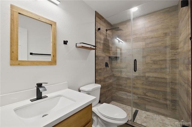 bathroom with vanity, a shower with shower door, and toilet