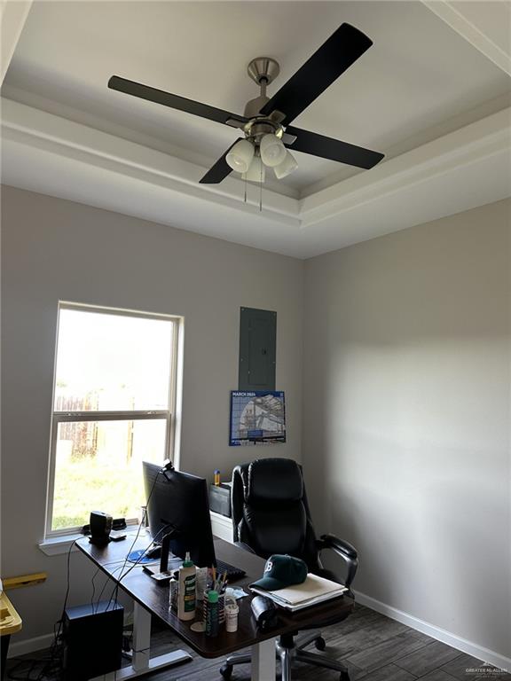 office featuring a tray ceiling, electric panel, ceiling fan, and hardwood / wood-style flooring