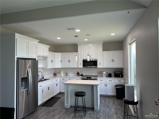 kitchen featuring sink, a breakfast bar, appliances with stainless steel finishes, white cabinetry, and a kitchen island