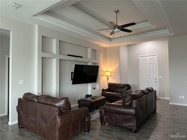 living room with a raised ceiling, dark hardwood / wood-style floors, and ceiling fan