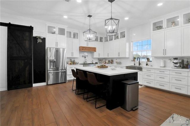 kitchen featuring white cabinets, stainless steel refrigerator with ice dispenser, a barn door, and a kitchen island