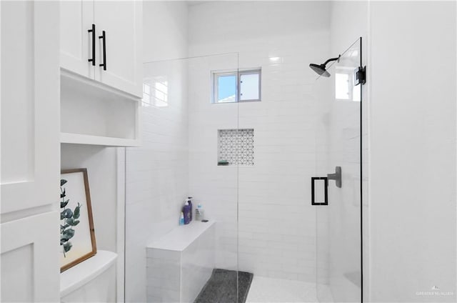 bathroom with a wealth of natural light, a shower with shower door, and toilet