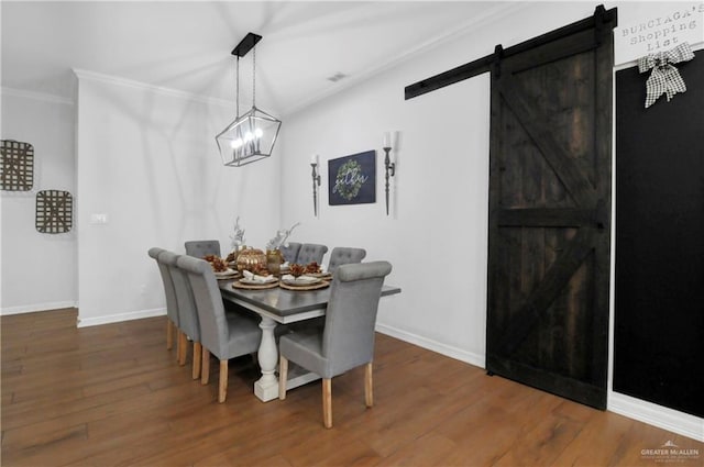 dining room featuring a barn door, crown molding, and hardwood / wood-style floors