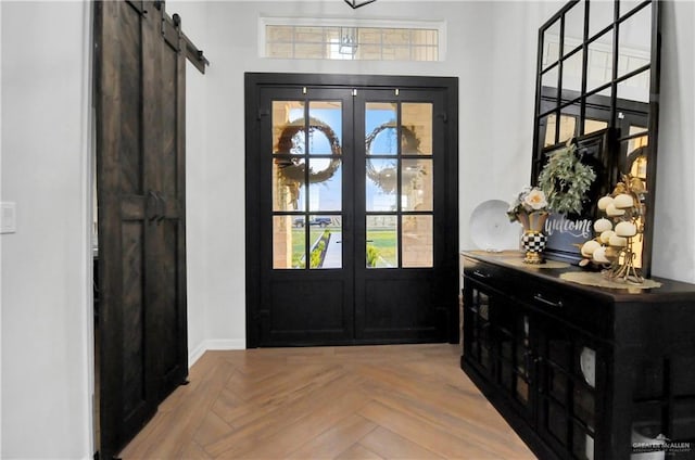 entrance foyer with a barn door, french doors, and light parquet flooring